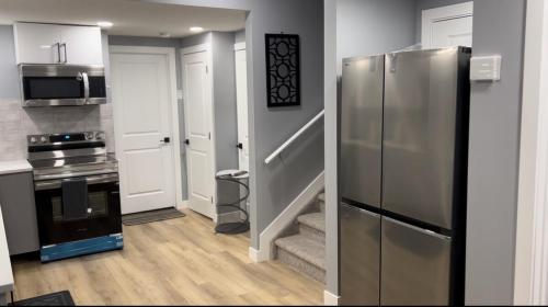 a kitchen with a stainless steel refrigerator and a staircase at Blissful Nest - Cozy, Classy 2 Bedroom Private Suite Netflix, free Parking, 20 minutes to West Edmonton Mall and Airport in Edmonton