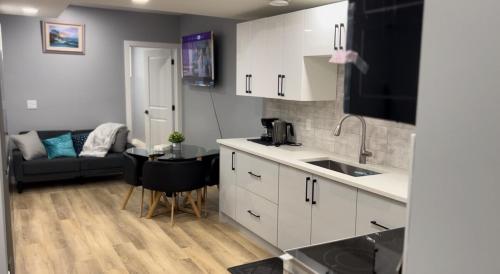 a kitchen with white cabinets and a couch in a room at Blissful Nest - Cozy, Classy 2 Bedroom Private Suite Netflix, free Parking, 20 minutes to West Edmonton Mall and Airport in Edmonton