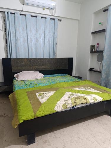 a bedroom with a bed with a green comforter at Hamdan's Guest House in Karachi