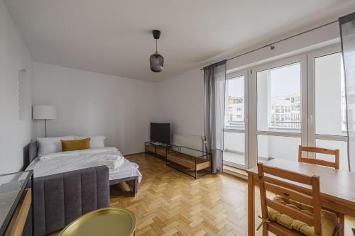 a living room with a couch and a table and a tv at Katowicka Comfort Apartment by BookingHost in Poznań