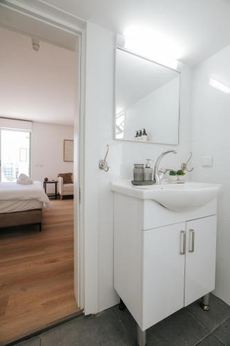 a white bathroom with a sink and a mirror at 175 Design Residence - With mamad in Tel Aviv