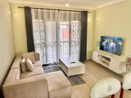 a living room with a couch and a tv at 2Bedroom flat, free Wi-Fi near acacia mall in Nalakonge