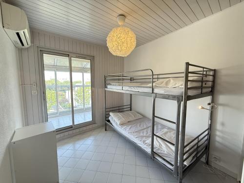 Cette chambre comprend 2 lits superposés et un lustre. dans l'établissement Sol-y-Days Soleil du Couchant Appartement avec terrasse et parking, à La Grande Motte