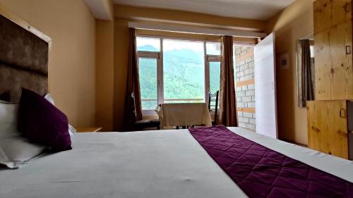 a bedroom with a large bed with a large window at Hotel Nirvana in Vashisht