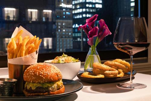 a table with a sandwich and french fries and a glass of wine at JW Marriott Essex House New York in New York