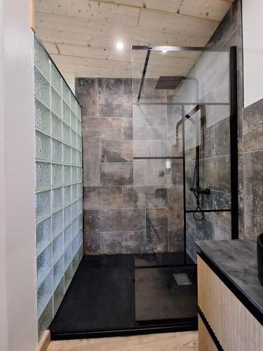 La salle de bains est pourvue d'une douche et d'une paroi en verre. dans l'établissement Eco-gîte cottage panoramique, terrasses, baby foot, 150 m2 rénové et agrandi en 2024, activités proposées, à Champagnac-le-Vieux