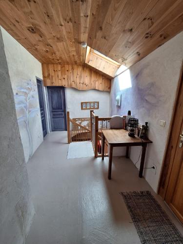 Cette chambre dispose d'un plafond en bois et d'une table. dans l'établissement Eco-gîte cottage panoramique, terrasses, baby foot, 150 m2 rénové et agrandi en 2024, activités proposées, à Champagnac-le-Vieux