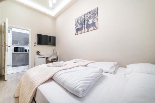 a white bedroom with two beds with white sheets at Dani Lux by Mital in Szeged