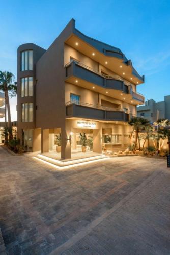 a large building with palm trees in front of it at Zeus Hotels Neptuno Beach in Amoudara Herakliou