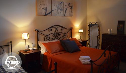 a bedroom with an orange bed with two lamps and a mirror at Bed and Breakfast Bike in Bagnoregio
