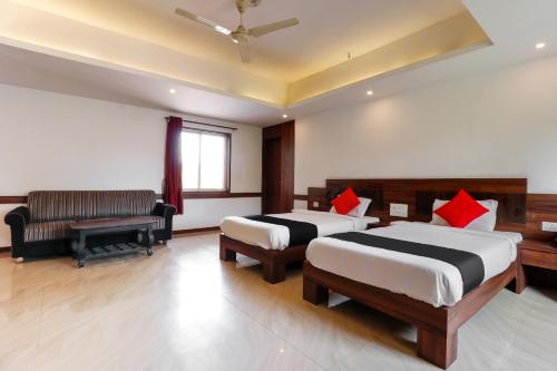 a hotel room with two beds and a couch and a window at Capital O Sai Arya Residency in Mangalore