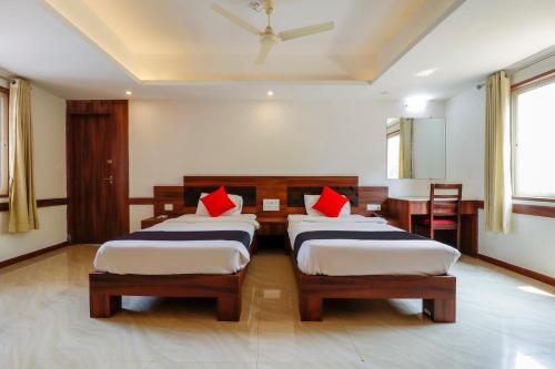 a bedroom with two beds and a table and chairs at Capital O Sai Arya Residency in Mangalore
