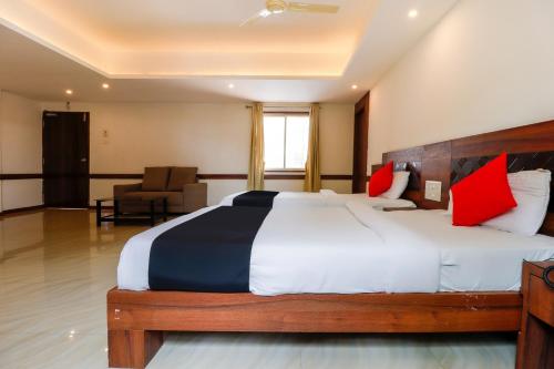 a bedroom with a large bed with red and black pillows at Capital O Sai Arya Residency in Mangalore