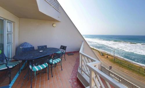 a balcony with a table and chairs and the ocean at 24 Isikhulu Umdloti Beachfront in Umdloti