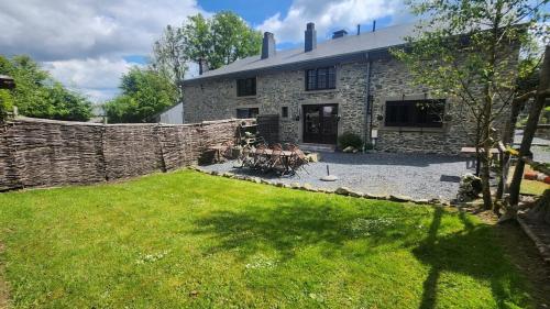 a stone house with a table in a yard at La Ferme Aux Bois in Houffalize