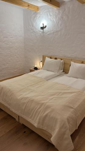 a bedroom with a large bed with white sheets at Andolia in Moieciu de Sus