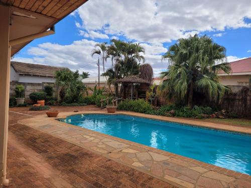 a swimming pool in a yard with palm trees at At Home Apartments in Mokopane