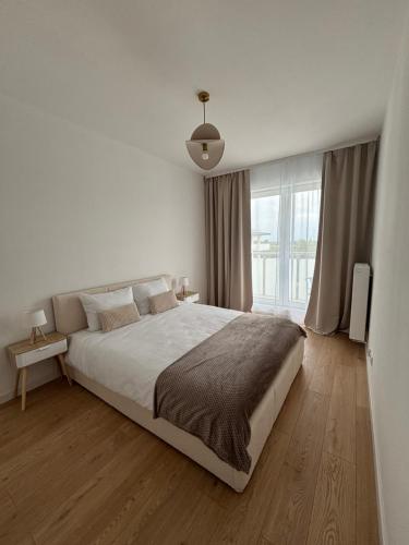 a white bedroom with a large bed and a window at Apartament 21 in Suwałki