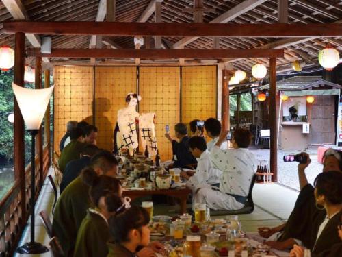 a group of people sitting at tables in a room at Takao Kanko Hotel in Kyoto