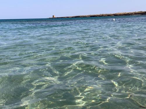 a large body of water with a lighthouse in the background at Madre Terra Airport Apartment & Rooms in Terrasini