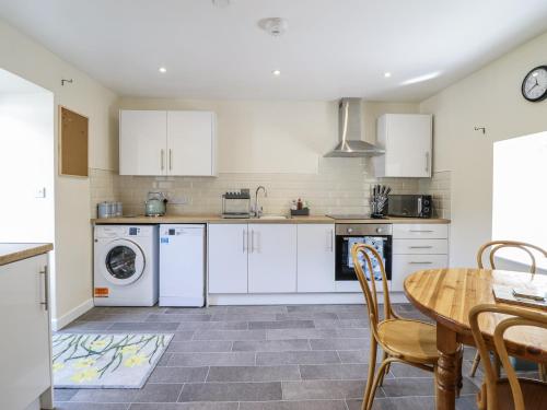 a kitchen with white cabinets and a table and chairs at 1 Y Llew in Llandinam