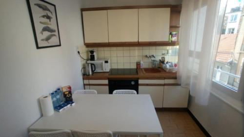 une petite cuisine avec une table et des chaises blanches dans l'établissement BUCER Strasbourg Parking, à Strasbourg
