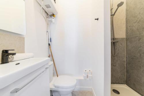 une salle de bain blanche avec toilettes et douche dans l'établissement Charmant 2 pieces central Les Halles a deux pas, à Paris