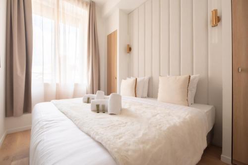 - une chambre avec un grand lit blanc et des oreillers blancs dans l'établissement Chic Flat in Paris Center, à Paris