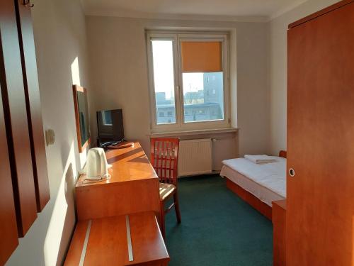 a small room with a bed and a desk with a telephone at Dom Studencki Rubin in Kalisz