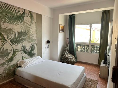 Un dormitorio con una cama y una ventana grande. en Habitación individual con baño compartido, en Algeciras