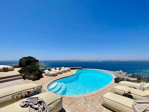 Una piscina con tumbonas y vista al mar. en Villa Tavani Agios Ioannis Mykonos, en Agios Ioannis Mykonos
