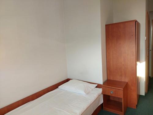 a small bedroom with a bed and a wooden cabinet at Dom Studencki Rubin in Kalisz