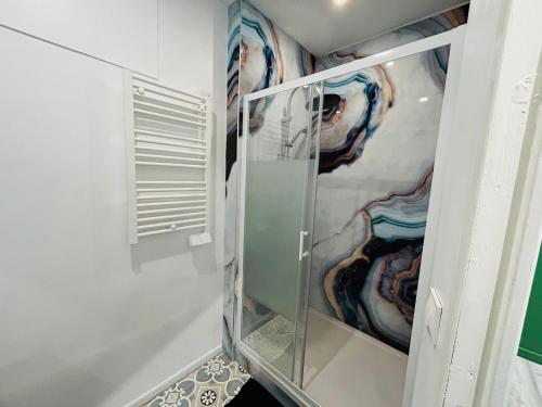 een glazen kast in een badkamer met schilderijen aan de muur bij Appartement Nid Douillet Plus in Tourcoing