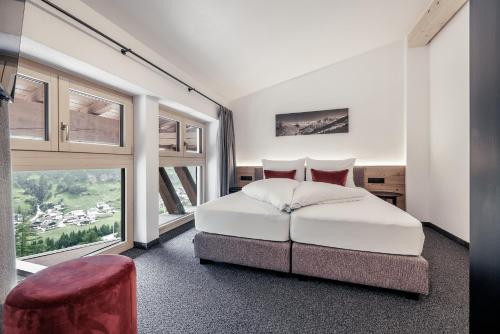 a bedroom with a white bed and a large window at Leni Mountain Appartements in Sölden