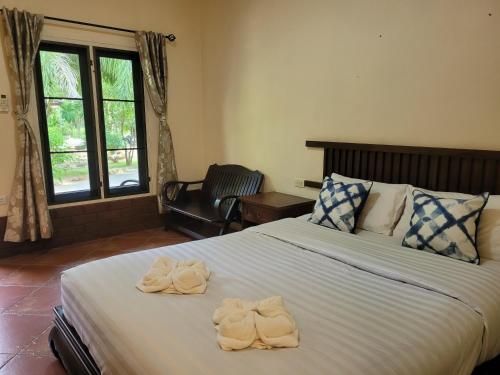 a bedroom with a large bed with towels on it at Baan Varintorn Suanphueng in Suan Phung