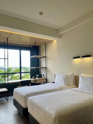 a hotel room with two beds and a large window at ATOOI Hotel Alam Sutera in Serpong