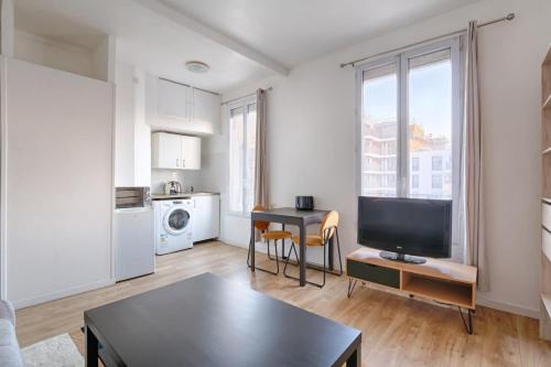 un salon avec une télévision et une table dans l'établissement Paul-Gillet Cosy Studio 2P, à Asnières-sur-Seine