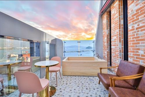 a room with a bath tub and a table and chairs at Jinhae 701 Hotel in Changwon