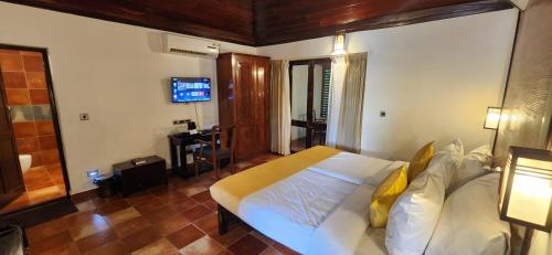 a bedroom with a large white bed and a television at Kumarakom Tharavadu - A Heritage Hotel, Kumarakom By Perfect Stays in Kumarakom