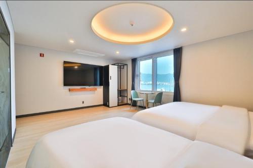 a bedroom with a large white bed and a table at Jinhae 701 Hotel in Changwon
