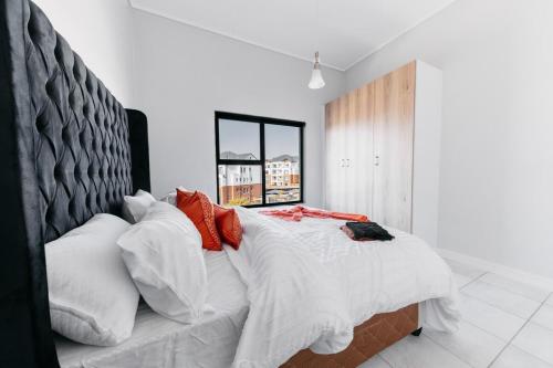 ein Schlafzimmer mit einem großen Bett mit roten und weißen Kissen in der Unterkunft Orange Blossom Luxury Apartment in Sandton