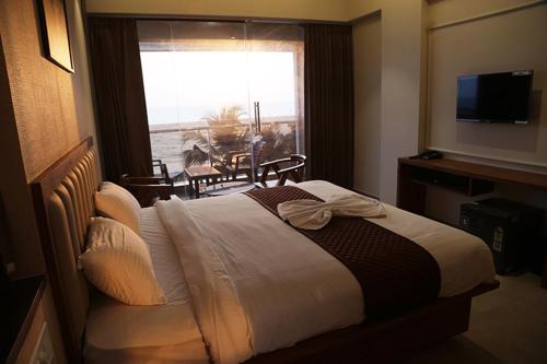 a hotel room with a bed and a window with a table at Palm Breeze Beach Resort in Mangalore