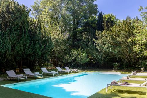 a swimming pool with chaise lounge chairs and trees at Les Demeures de Varennes, BW Signature Collection in Varennes-Jarcy