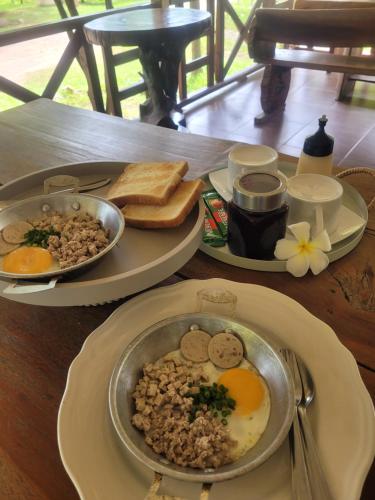 a table with two plates of food and eggs and toast at Baan Varintorn Suanphueng in Suan Phung