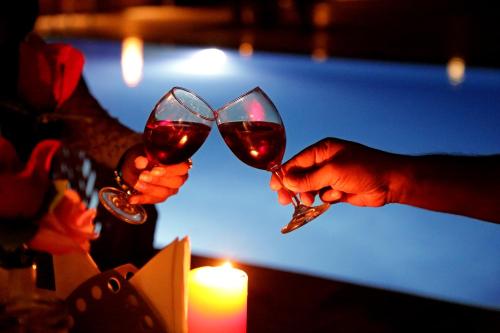 two people holding glasses of red wine next to a candle at Hotel Golden Haveli in Jaisalmer