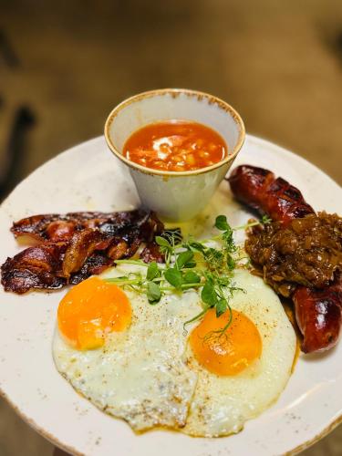 a plate of food with eggs and bacon and a sauce at Jasna SportHotel & SPA in Gliwice