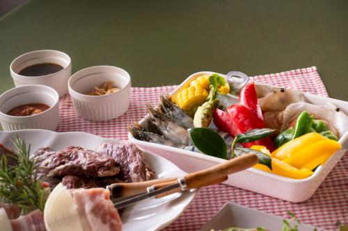 a table with a plate of food with meat and vegetables at Le Nessa Jyogasaki in Ito