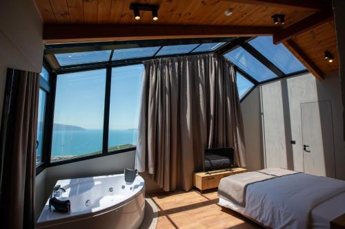 a bedroom with a tub and a bed and a window at Montis Agroturizëm Hotel Spa in Kaninë