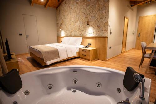 a large bath tub in a room with a bed at Montis Agroturizëm Hotel Spa in Kaninë