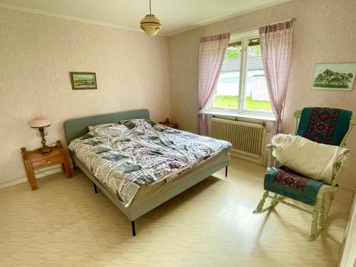 a bedroom with a bed and a chair and a window at Lovely Home in Högsby